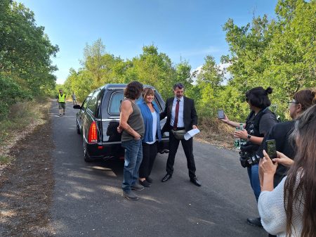 Photo de tournage où l'on voit un groupe d'acteurs posant pour une photo devant un corbillard noir